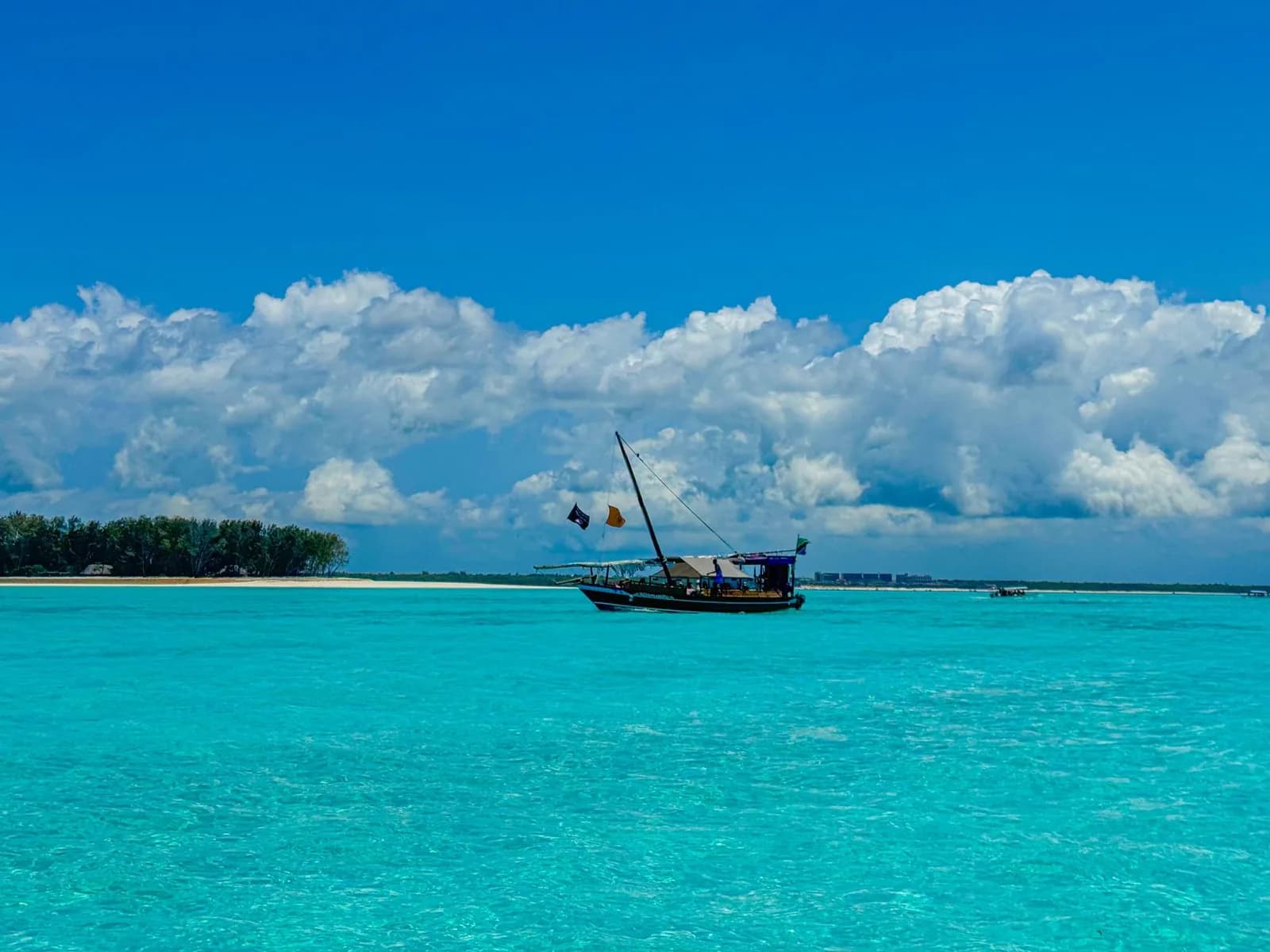 Traditional dhow on a flat turquoise lagoon in front of a sandbank, Zanzibar