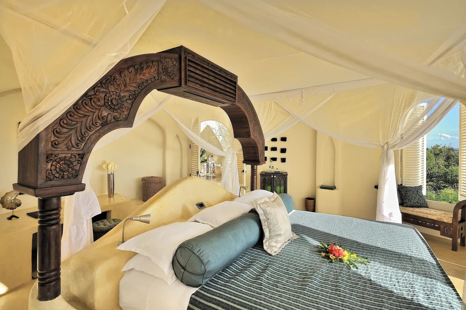 Carved Zanzibari wooden arch and canopied bed inside a suite at Elewana Kilindi Zanzibar, Kendwa