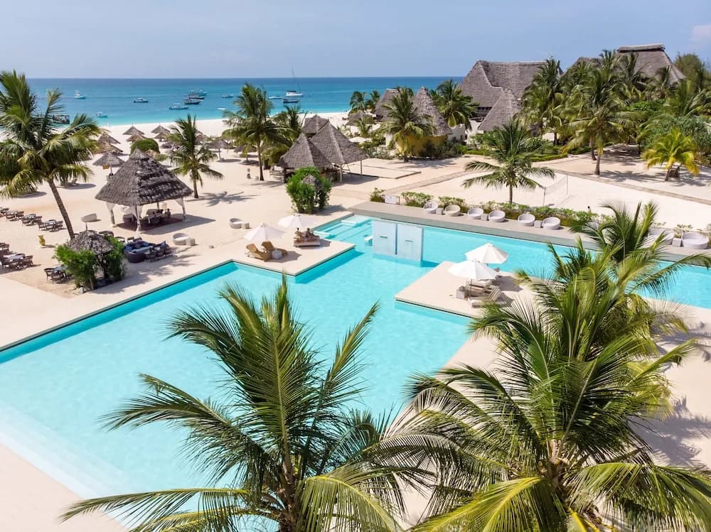 Aerial view of the lagoon pool, thatched beach pavilions and palm trees at Gold Zanzibar Beach House & Spa, Kendwa