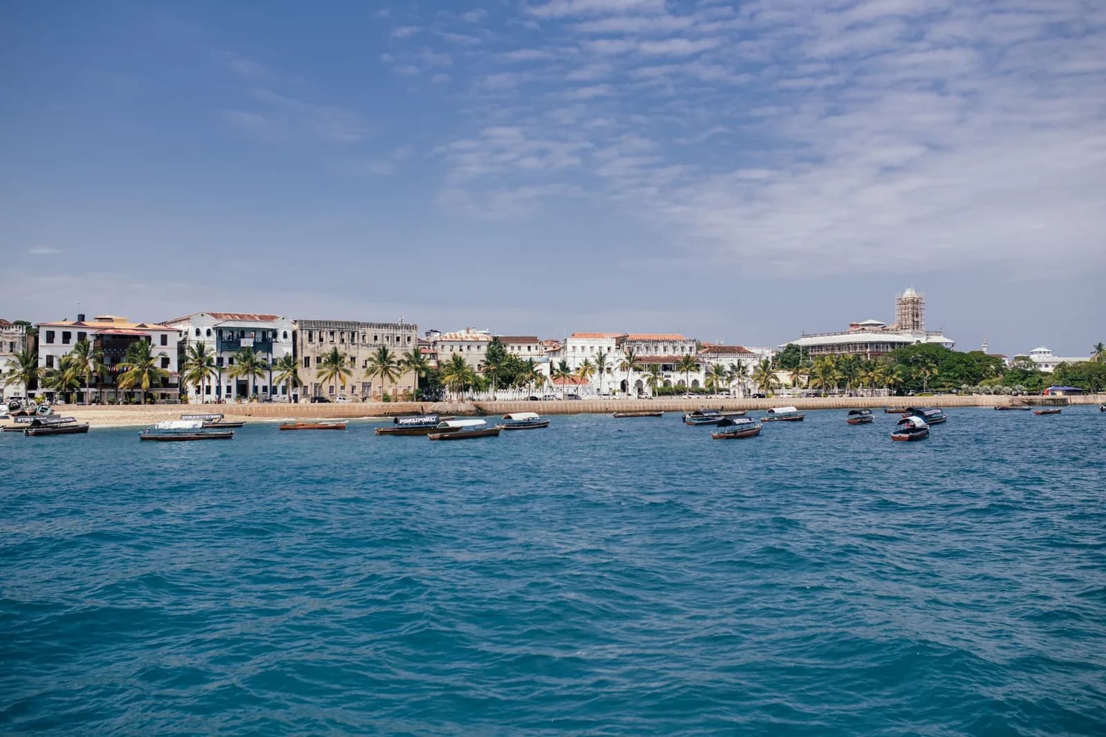 Stone Town seafront seen from the water, with the House of Wonders on the right, its clock tower wrapped in scaffolding
