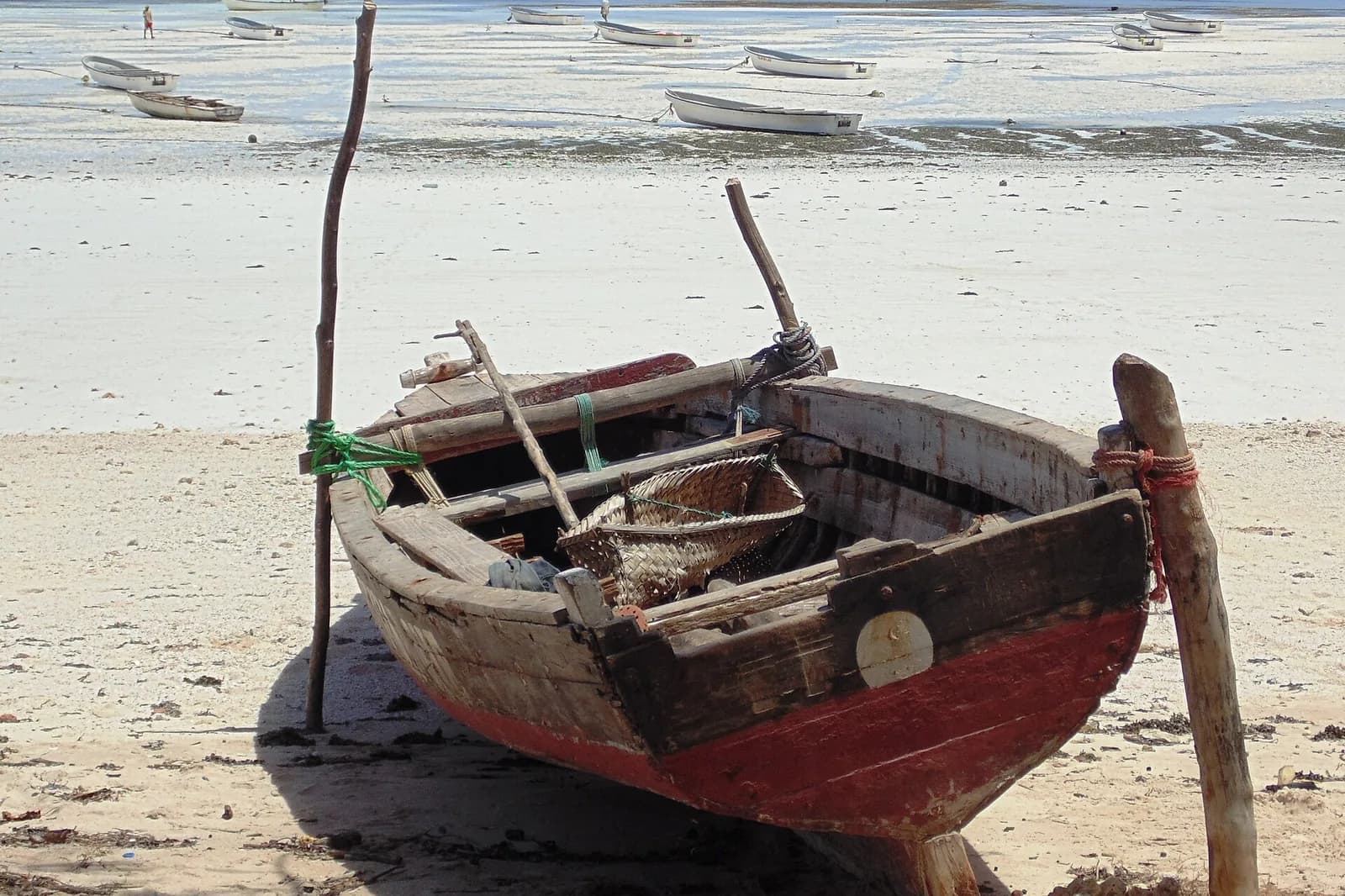 Wooden fishing boat beached on the white sand at low tide in Kizimkazi, south-west Zanzibar