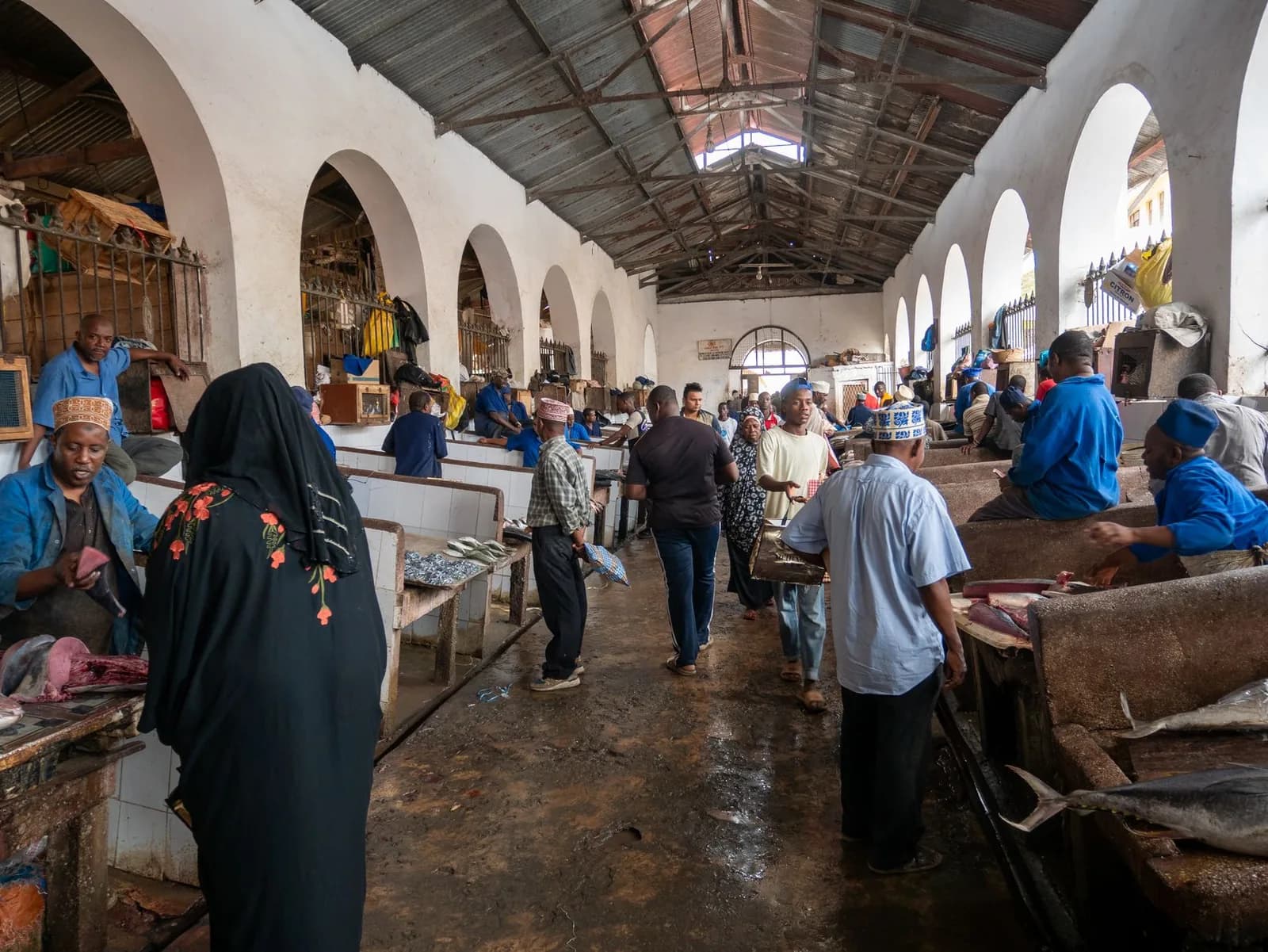 Stallholders and shoppers inside the arched hall of Darajani market, Stone Town