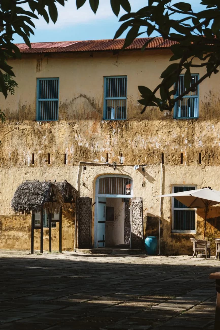 Ochre walls, a thatched notice board and cafe tables in the courtyard of the Old Fort, Stone Town