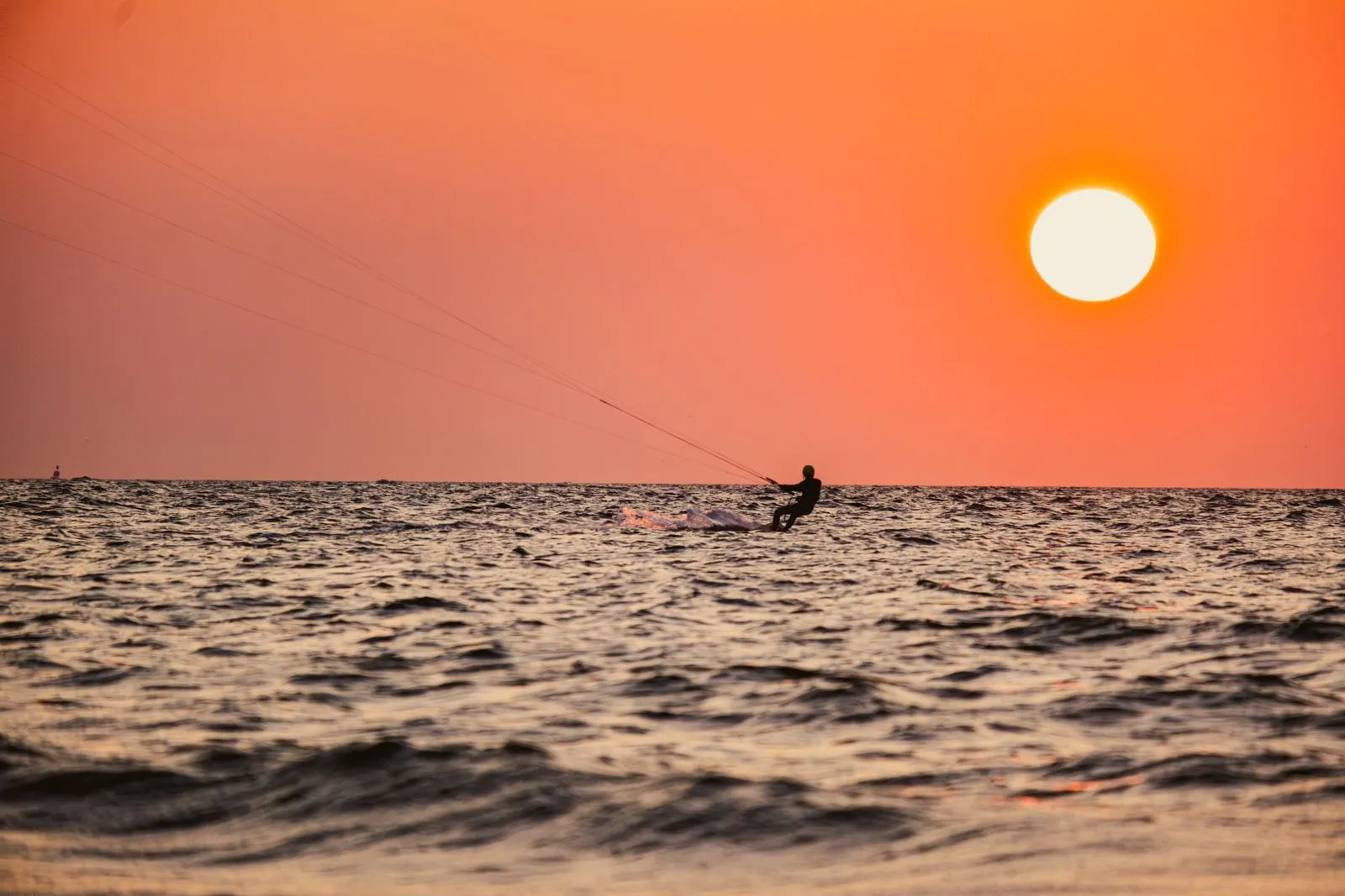 A kitesurfer silhouetted against the setting sun off the south east coast of Zanzibar