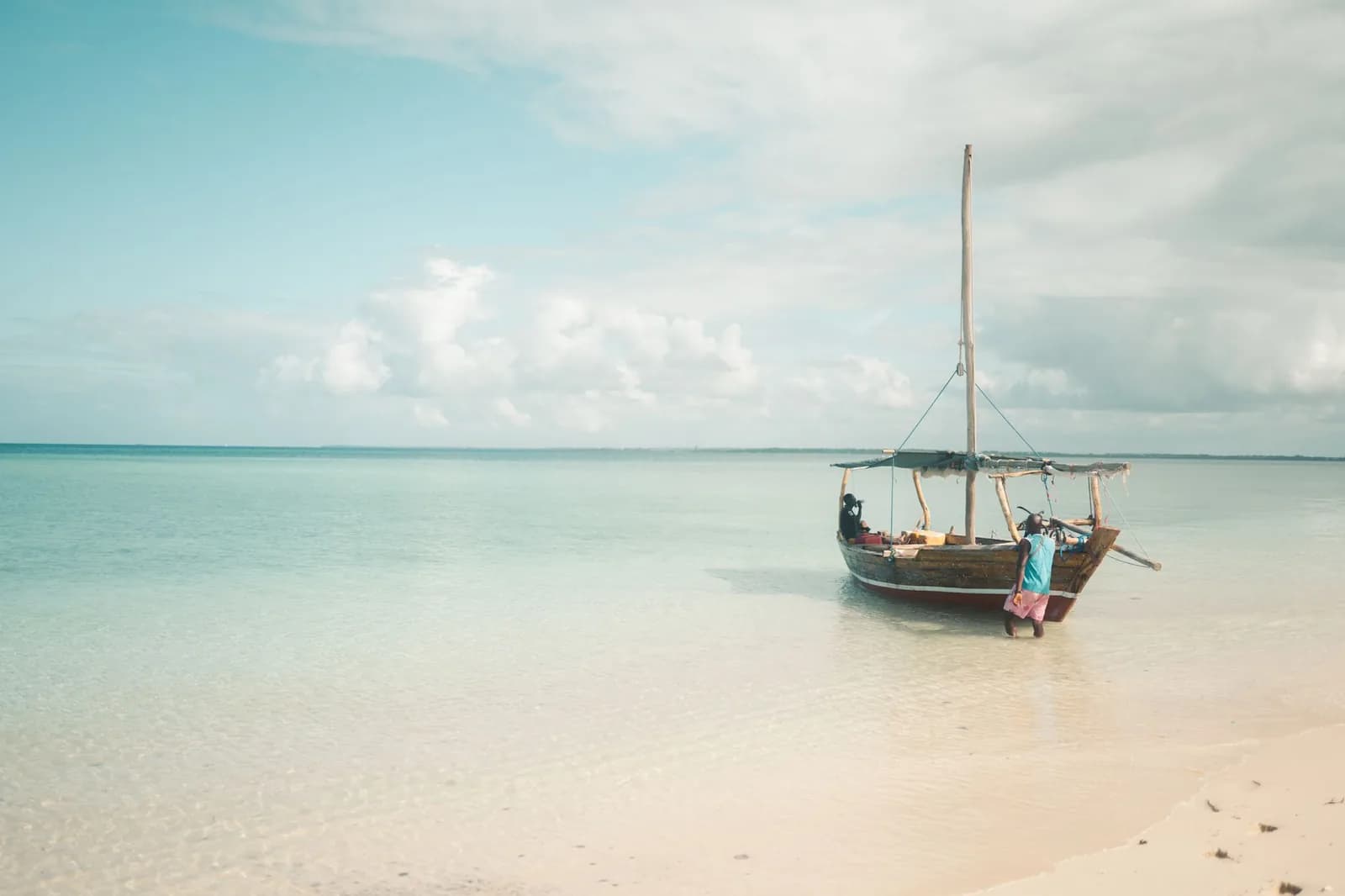 Wooden dhow moored in shallow water off a white sand beach in Zanzibar
