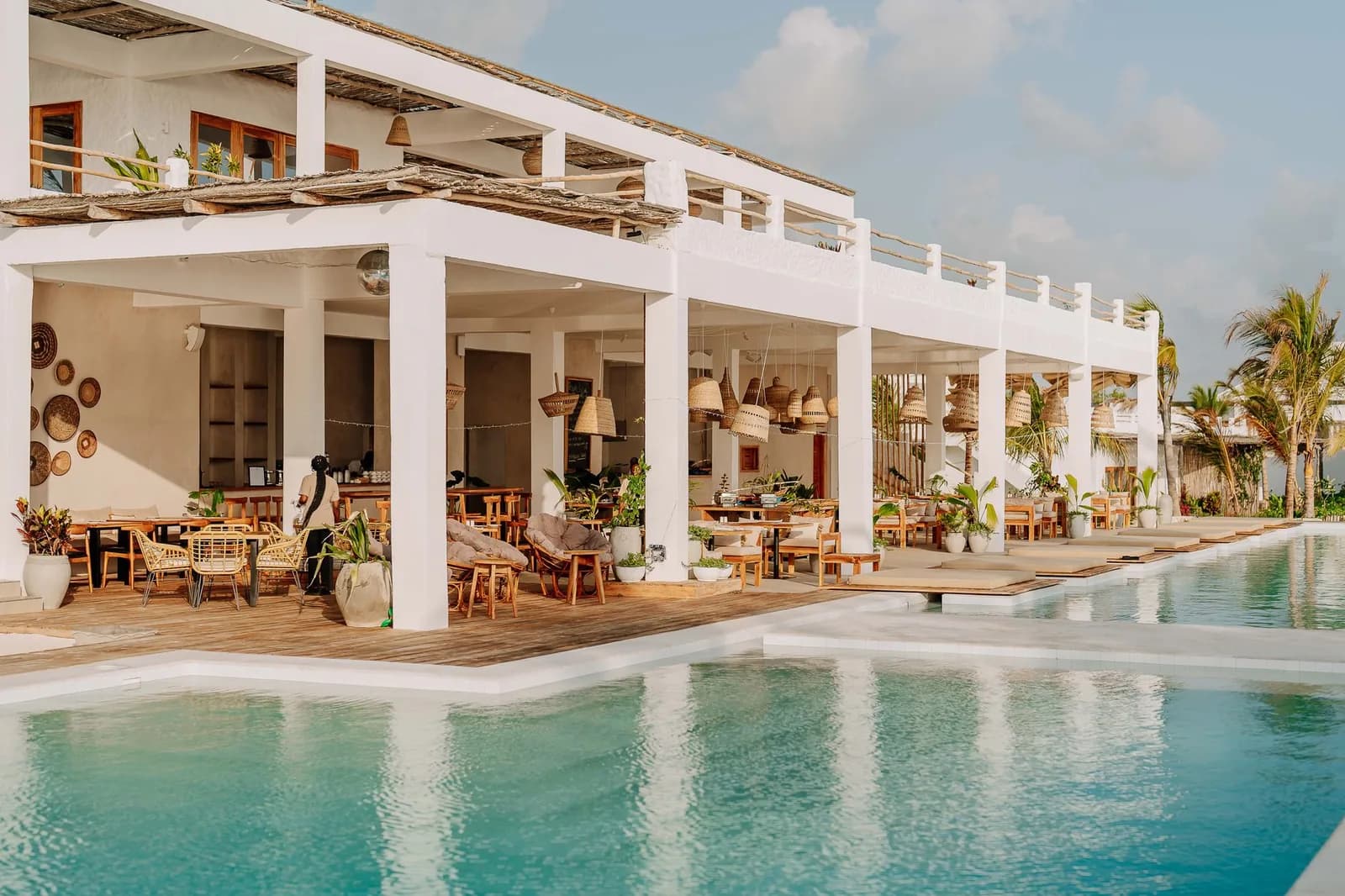White resort building with an open restaurant terrace above a long pool in Jambiani, Zanzibar
