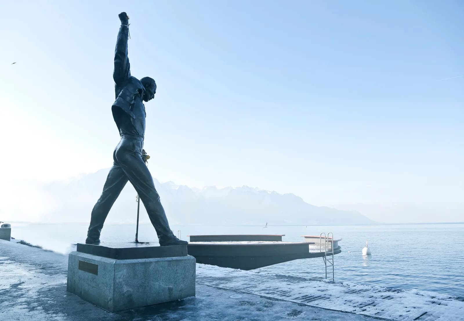 The bronze statue of Freddie Mercury with his fist raised on the shore of Lake Geneva in Montreux, Switzerland, mountains behind