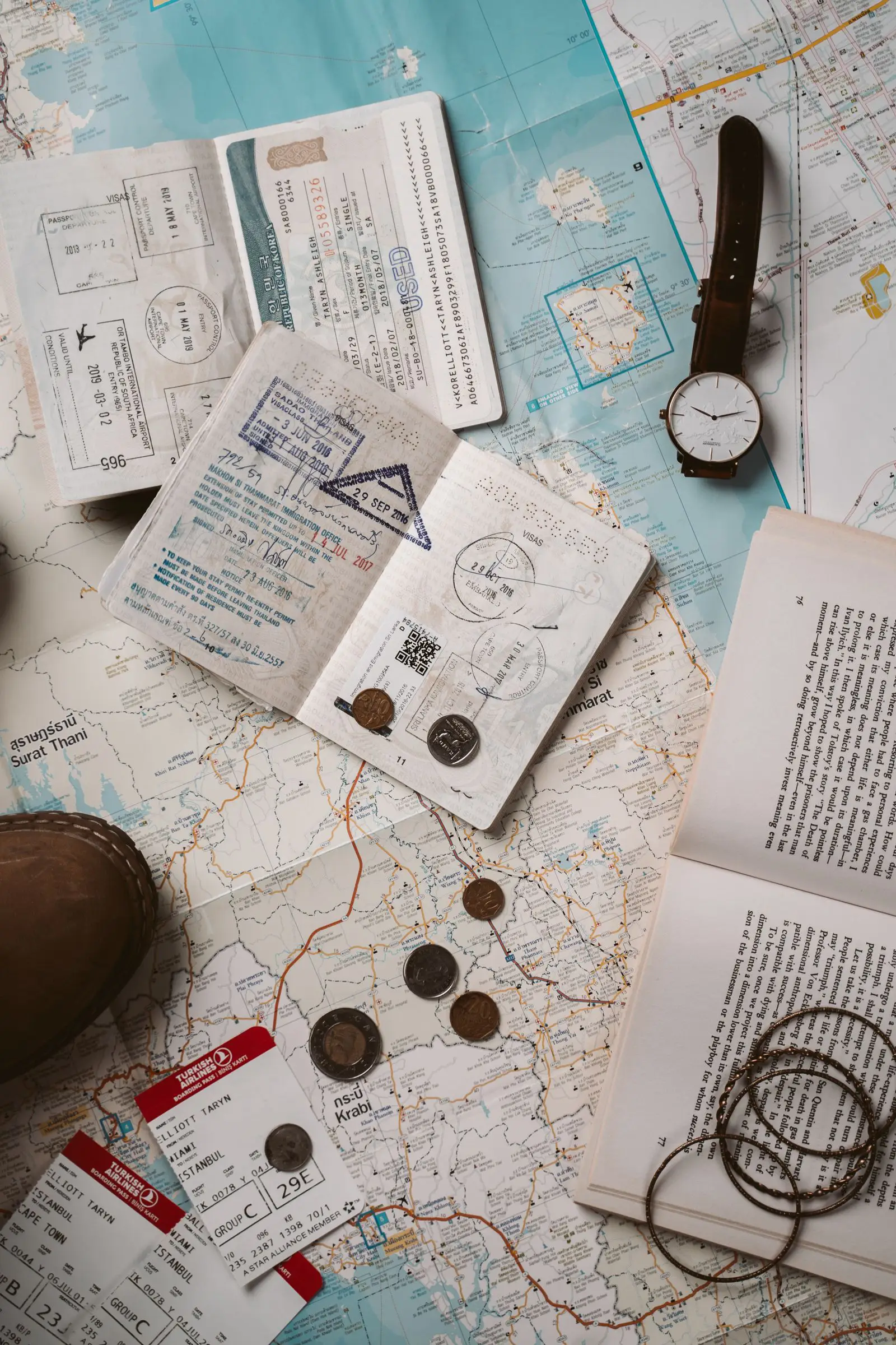 Passports covered in entry stamps, boarding passes and coins spread over a travel map